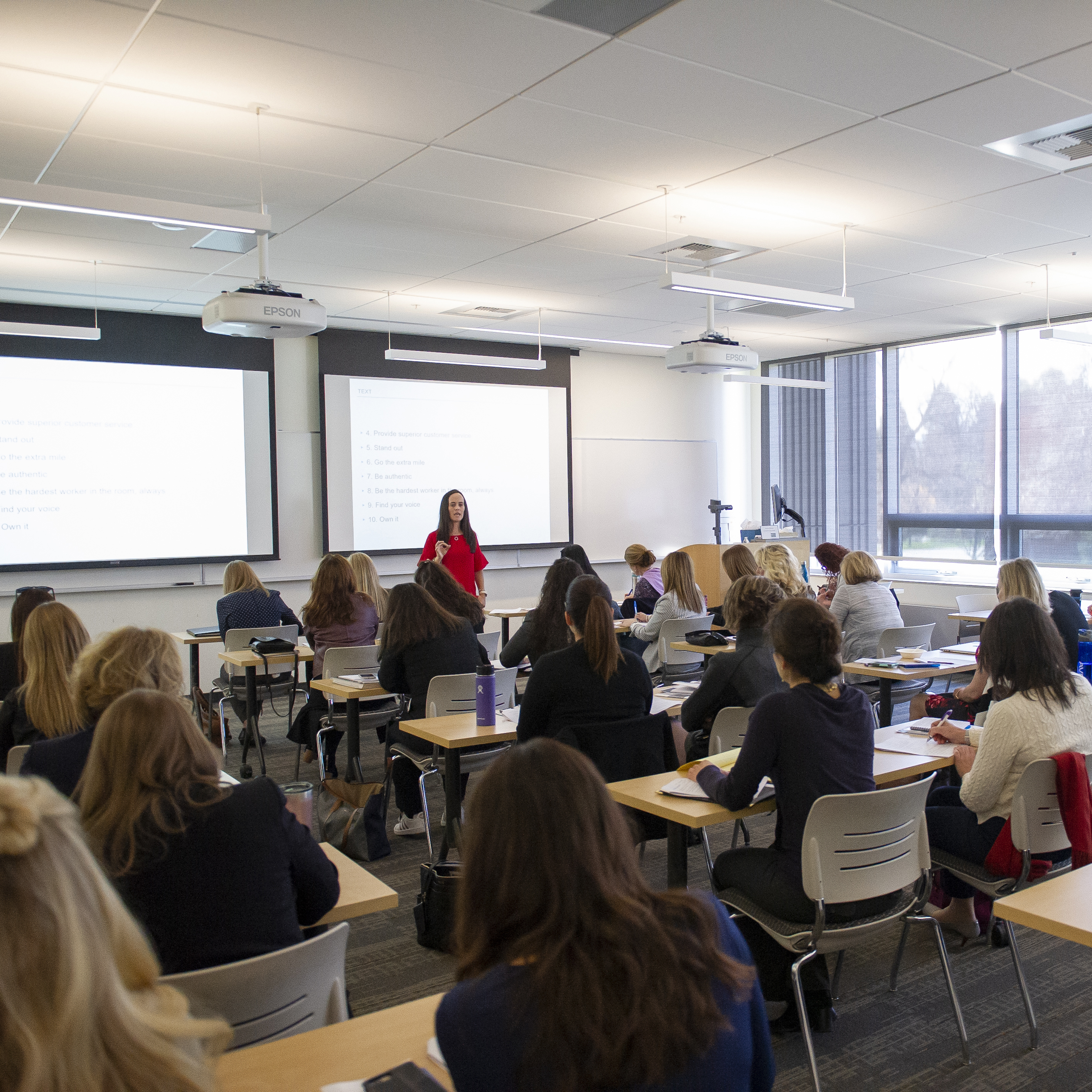 An alumna presents in front of a classroom full of people