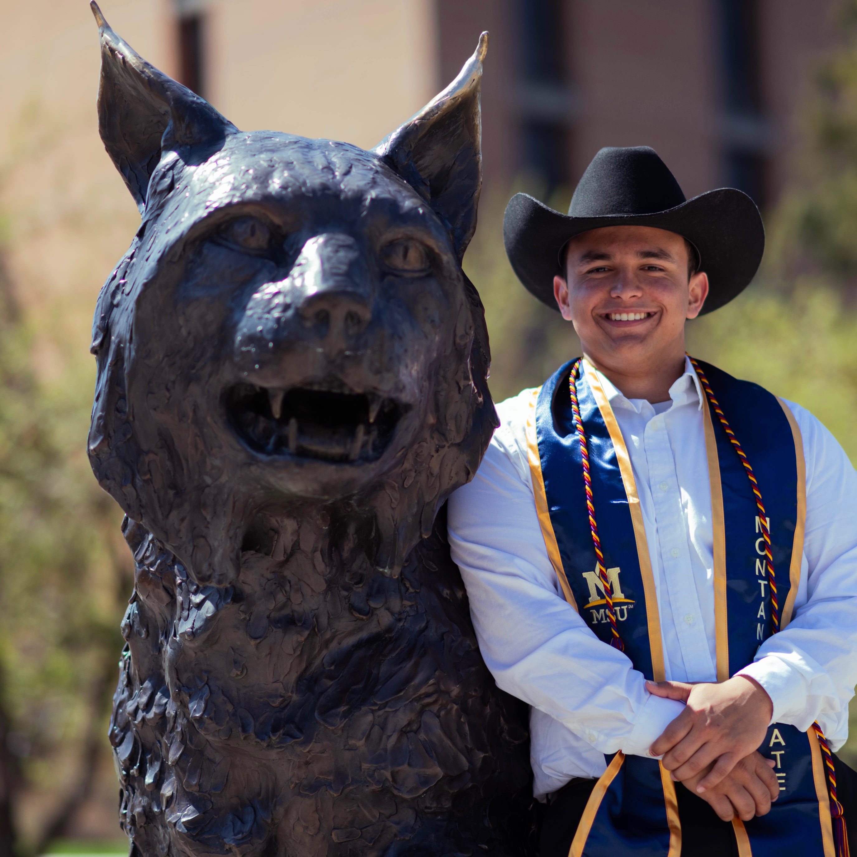 Ander next to the bobcat statue 