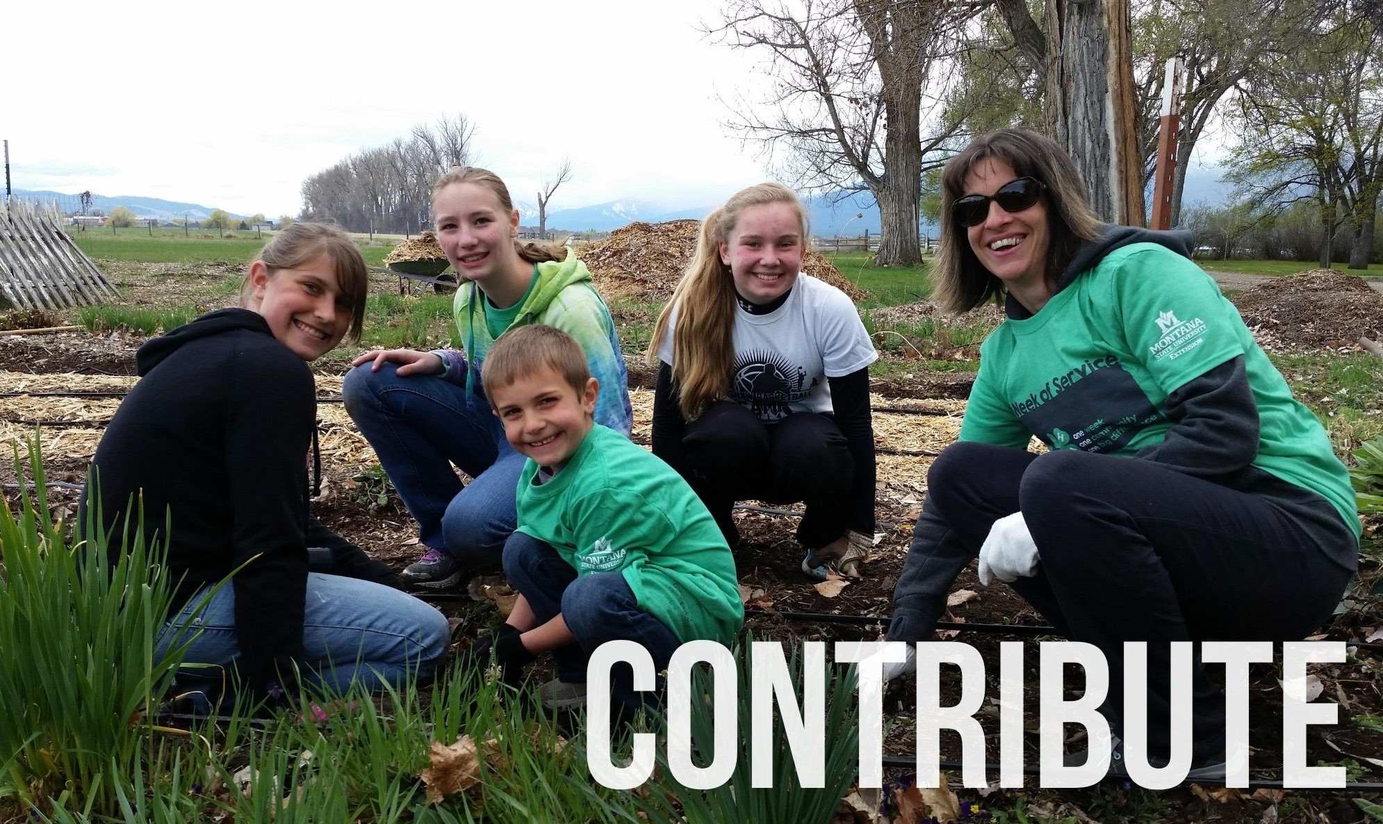 A female volunteer gardens with kids.