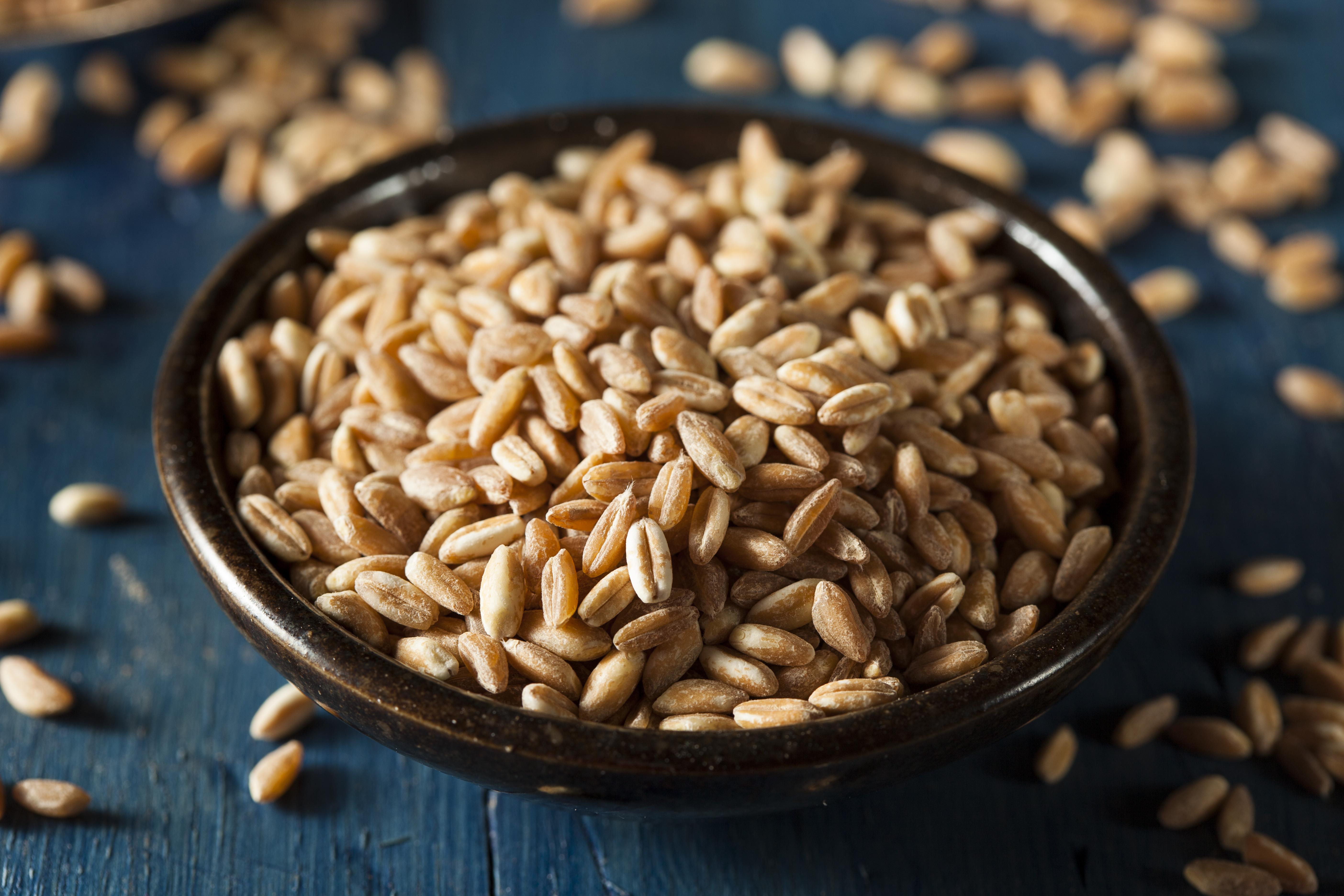 A wooden bowl containing pieces of grain.