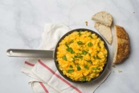 An image of macaroni and cheese in a skillet next to pieces of sliced bread.