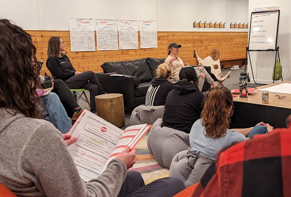 Small group of women holding learning books listening to another woman speak. 