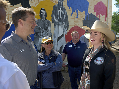 Participants in a community event conversing near a mural.