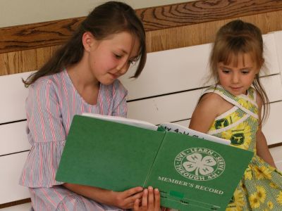 4-H Members Sitting on bench wearing 4-H clothing.