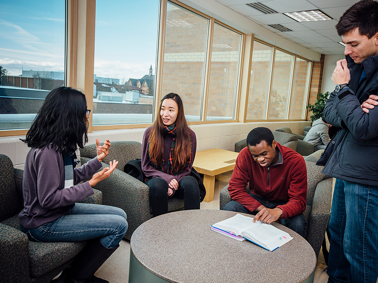 Four students in a lounge with a book
