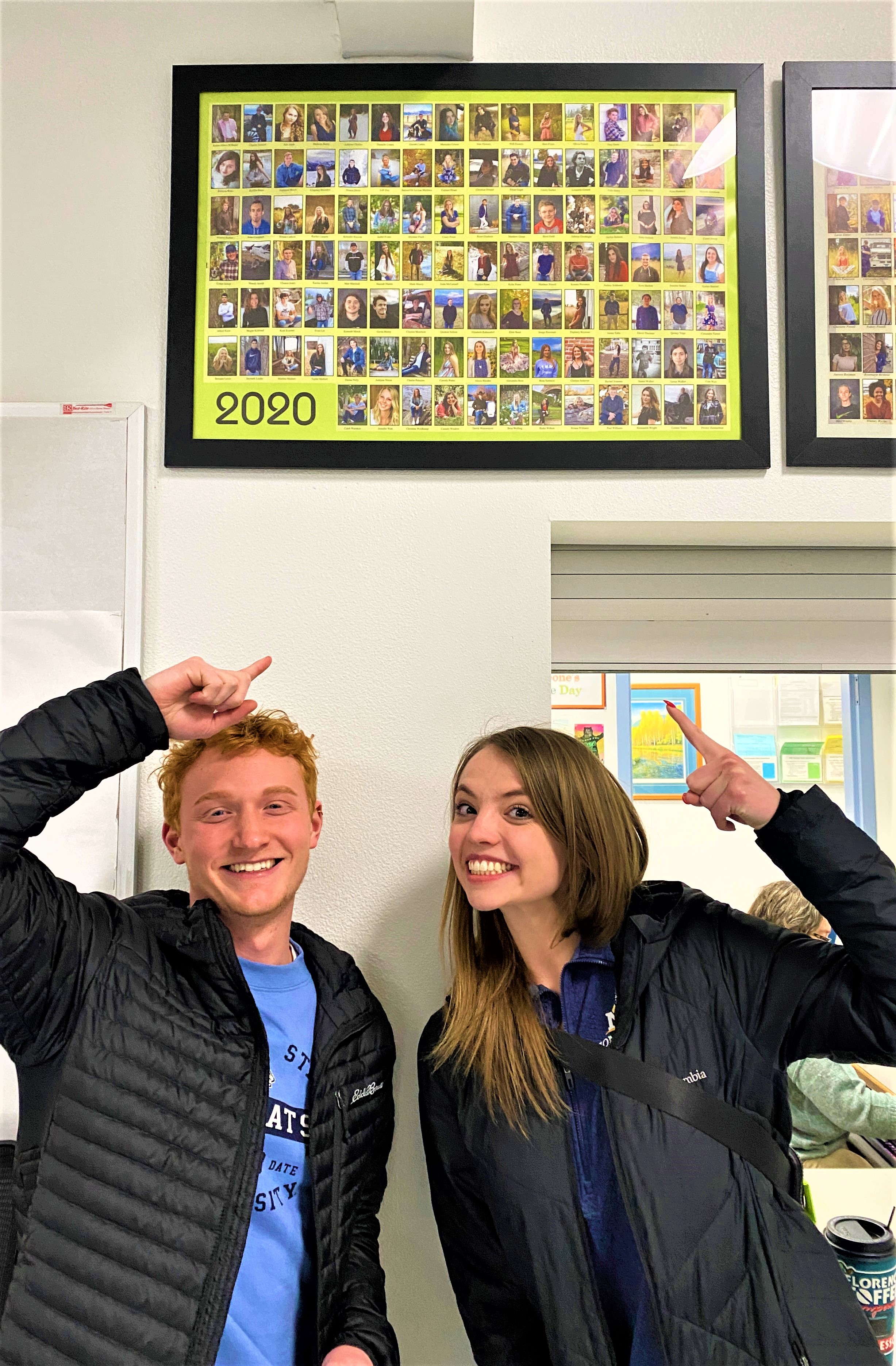 students pose in front of their high school photos 