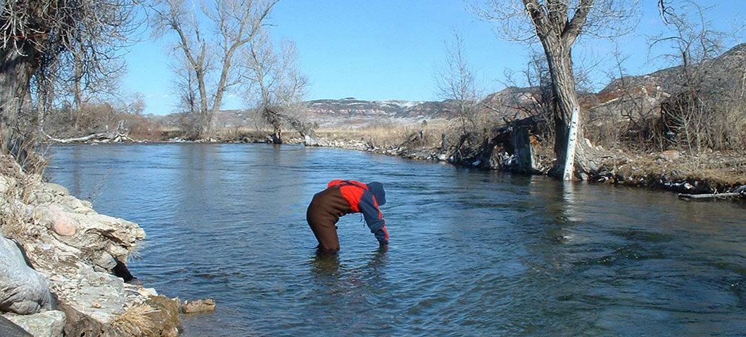 Person bent over the water in a river