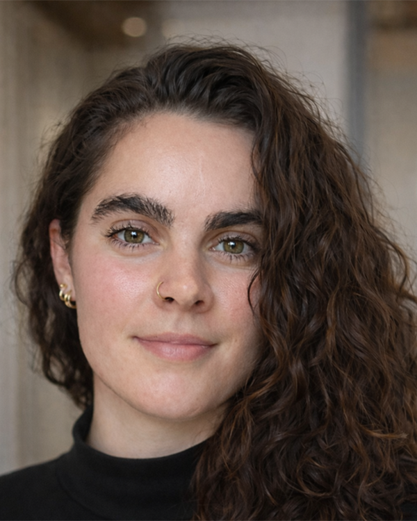 A person with long black hair with a hook nose ring wearing a black shirt
