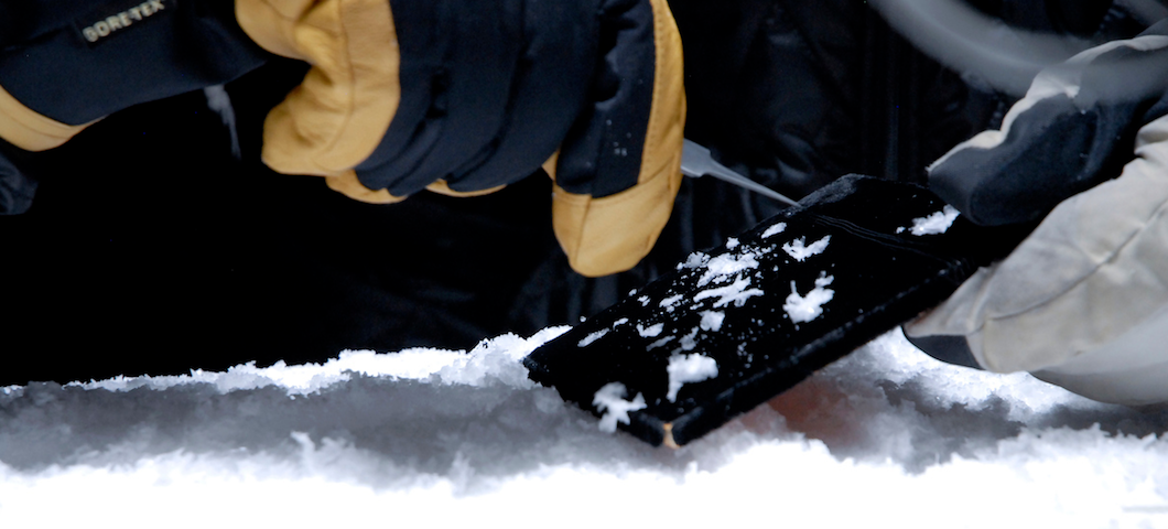 close-up photo of gloved hands tweezering snow crystals